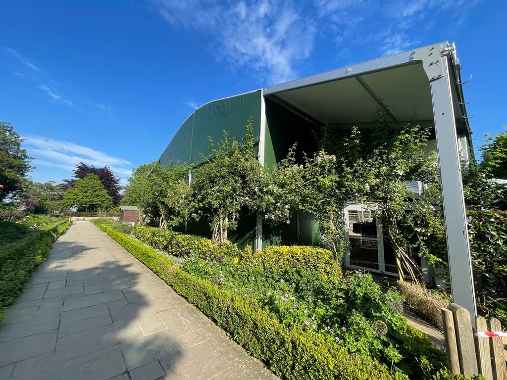 Temporary theatre marquee exterior set within landscaped country house gardens.