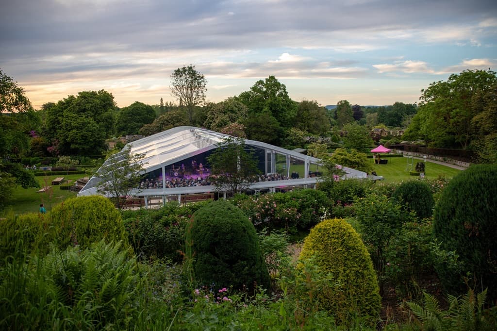 Temporary theatre marquee with stage in historic country house gardens in UK.